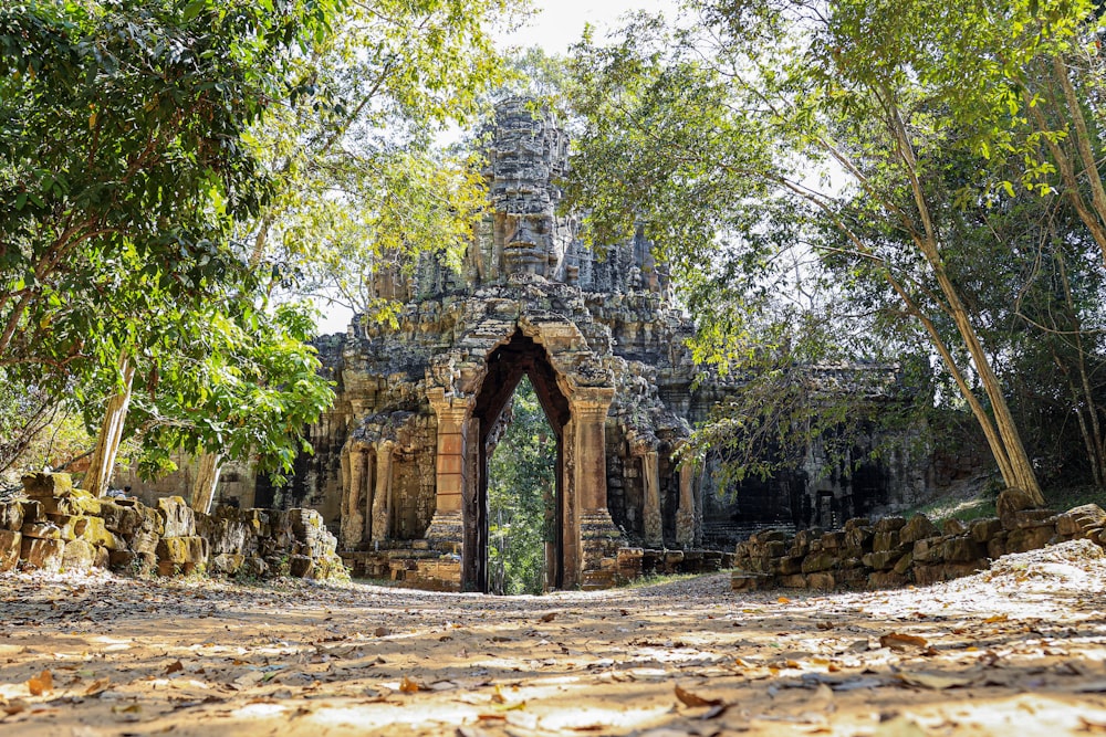 a stone gate surrounded by trees in a forest