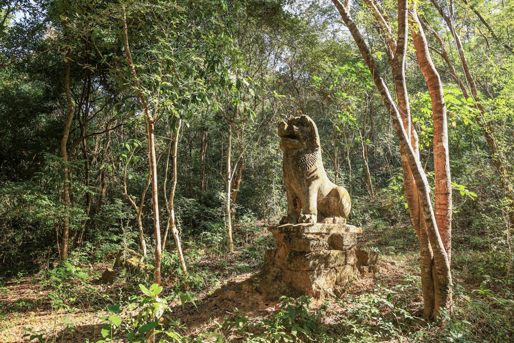 a statue of a lion in the middle of a forest