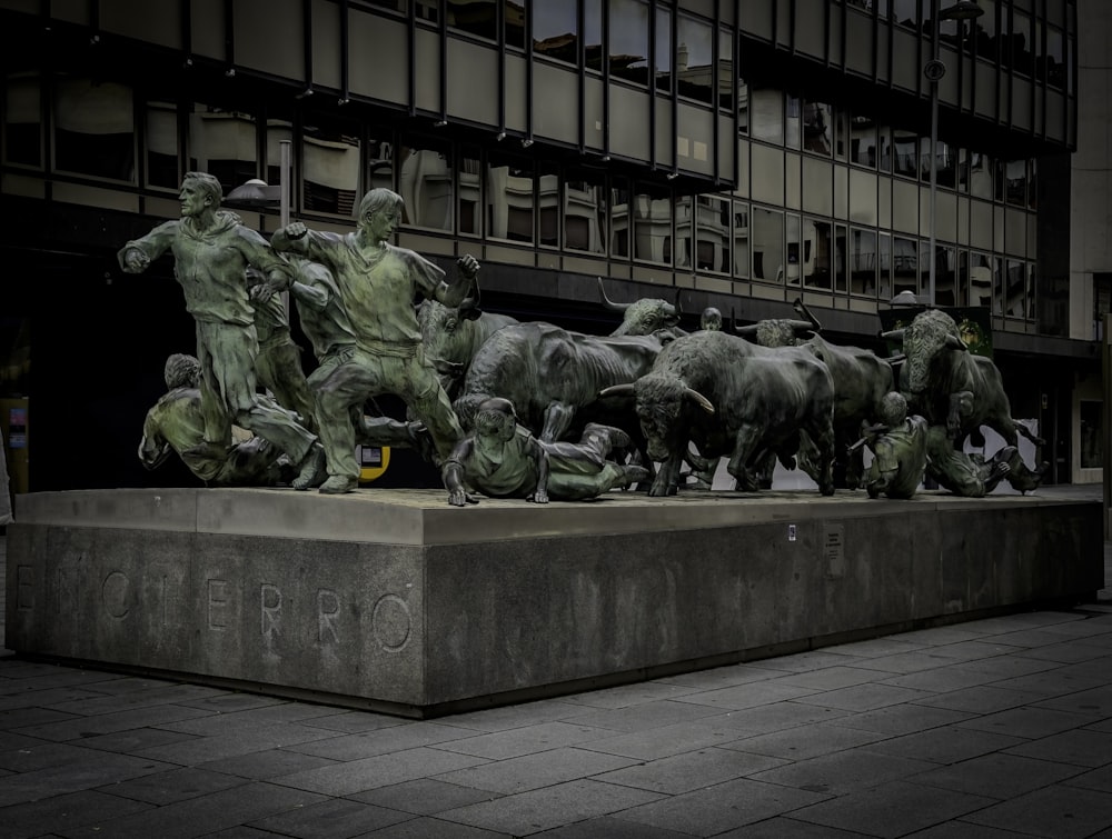 a group of statues of men and animals in front of a building
