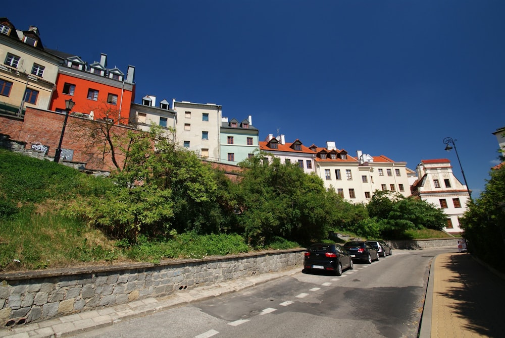 a row of houses on a hill with cars parked on the side