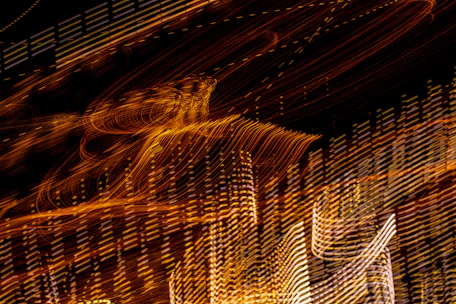 Close-up abstraction of warm golden light trails swirling over deep charcoal background symbolizing raw energy flow.