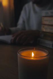 A cozy room with participants writing in notebooks, surrounded by books and warm lighting.
