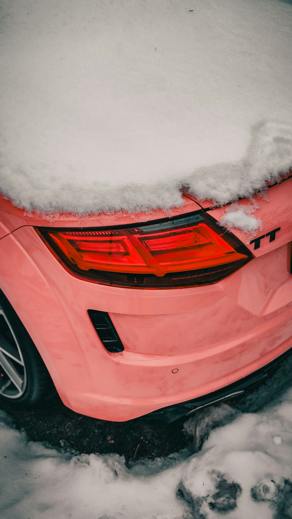 a pink car covered in snow on a street