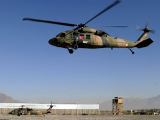 Modern minimalist training facility with helicopters and soldiers in action under clear skies.