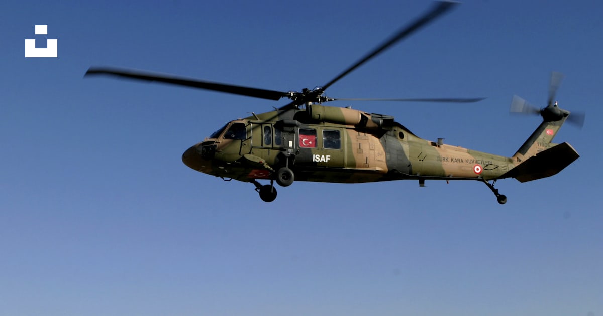 A military helicopter flying over a military base photo – Free Vehicle