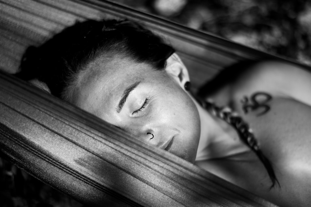 a woman laying in a hammock with her eyes closed