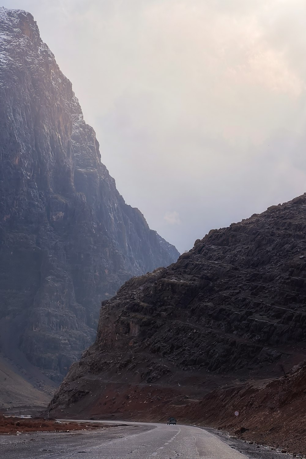 a car driving down a mountain road with a mountain in the background