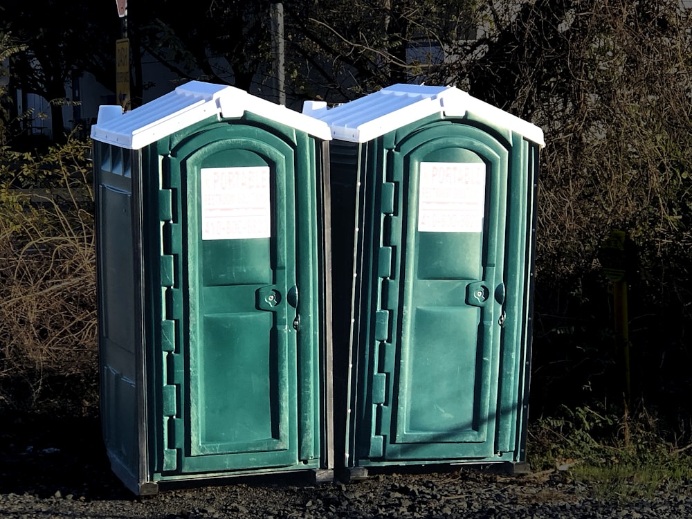 a couple of green portable toilets sitting next to each other
