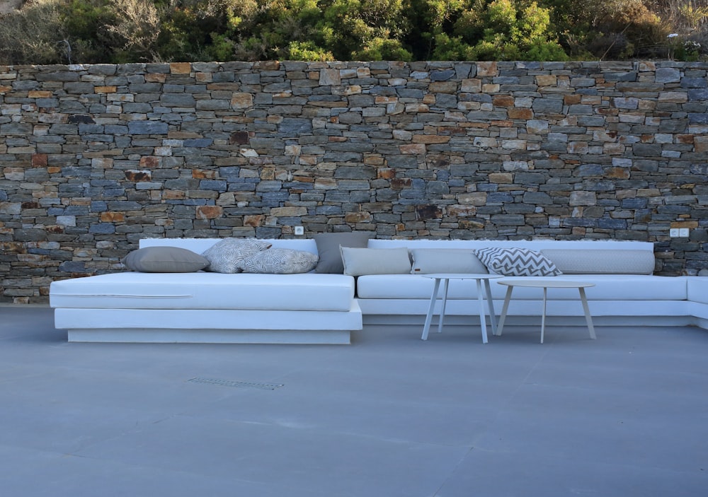 a white couch sitting next to a stone wall