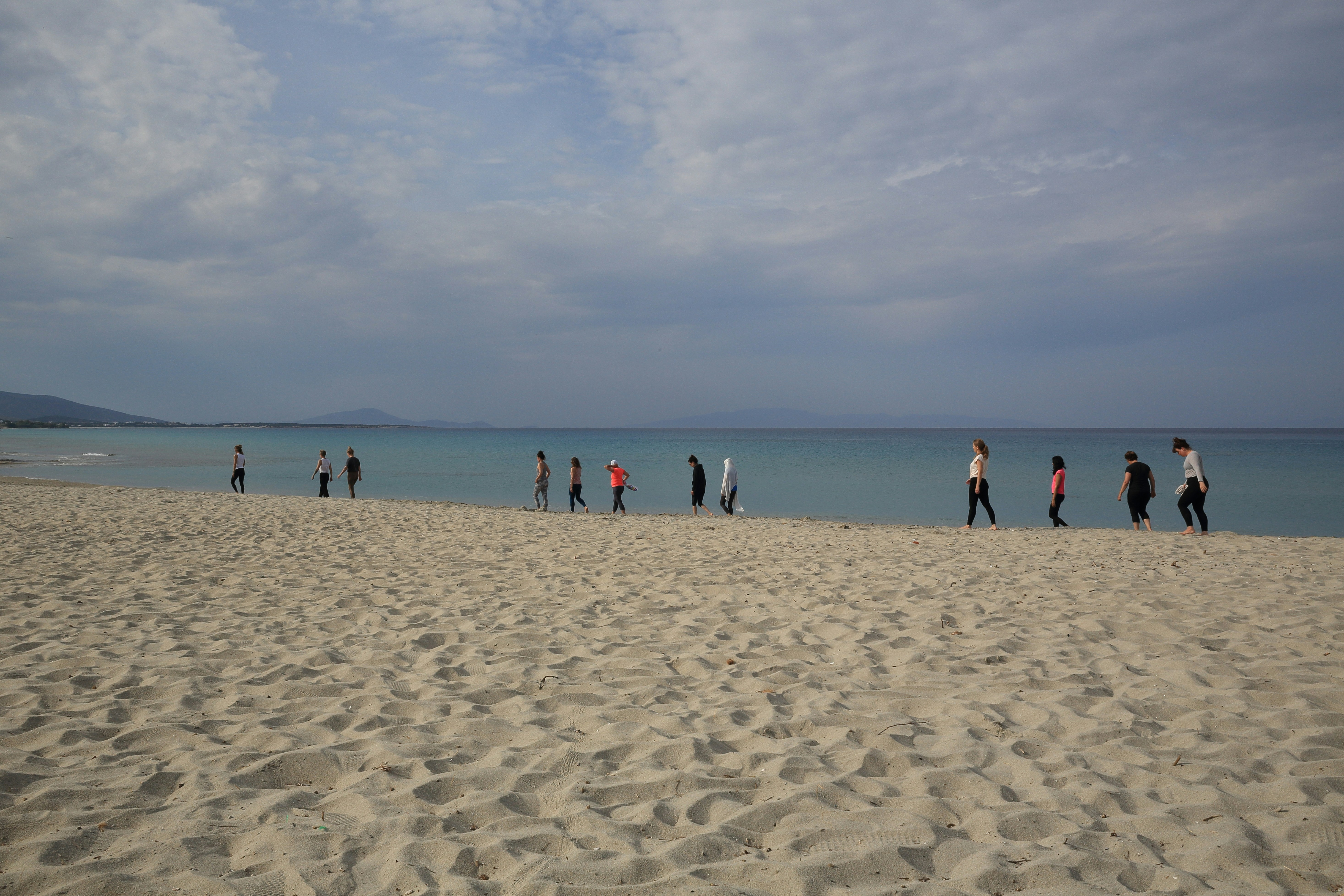 a group of people standing on top of a sandy beach