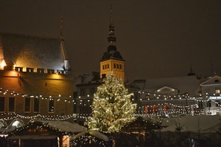 A cozy winter scene of a small town square decorated with Christmas lights and a festive tree.