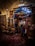 A beautifully decorated interior with an array of colorful, intricately patterned rugs hanging on the walls and covering the floor. The dim lighting creates a warm and cozy atmosphere, with the soft glow highlighting the textures and details of each rug. A doorway in the center reveals additional displays in a well-lit adjacent room.