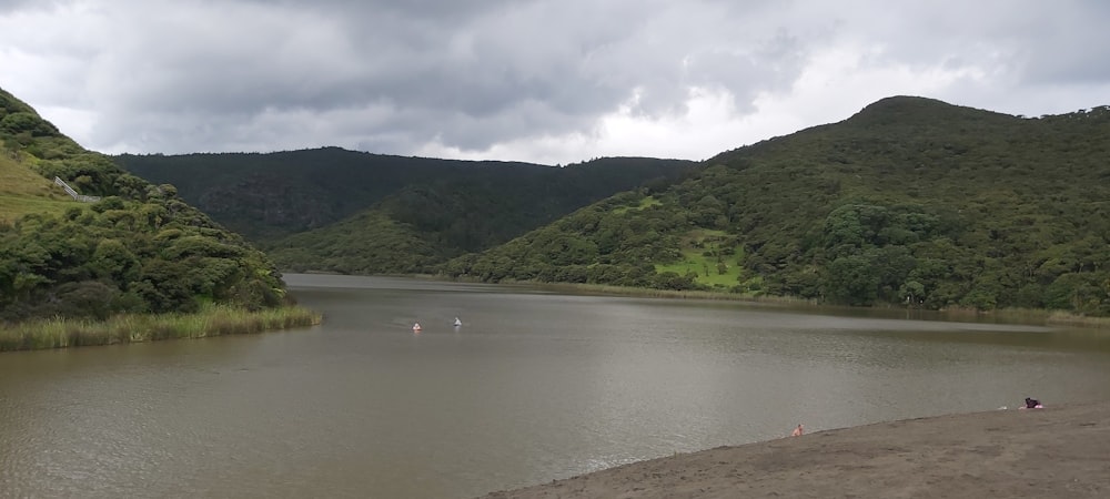 a body of water surrounded by mountains under a cloudy sky