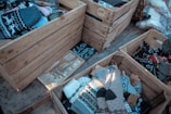 Wooden crates filled with woolen socks, some of which are patterned with traditional designs. There are price tags and a sign that reads 'Alpaca Woolen Socks' along with pricing information.