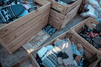 Wooden crates filled with woolen socks, some of which are patterned with traditional designs. There are price tags and a sign that reads 'Alpaca Woolen Socks' along with pricing information.