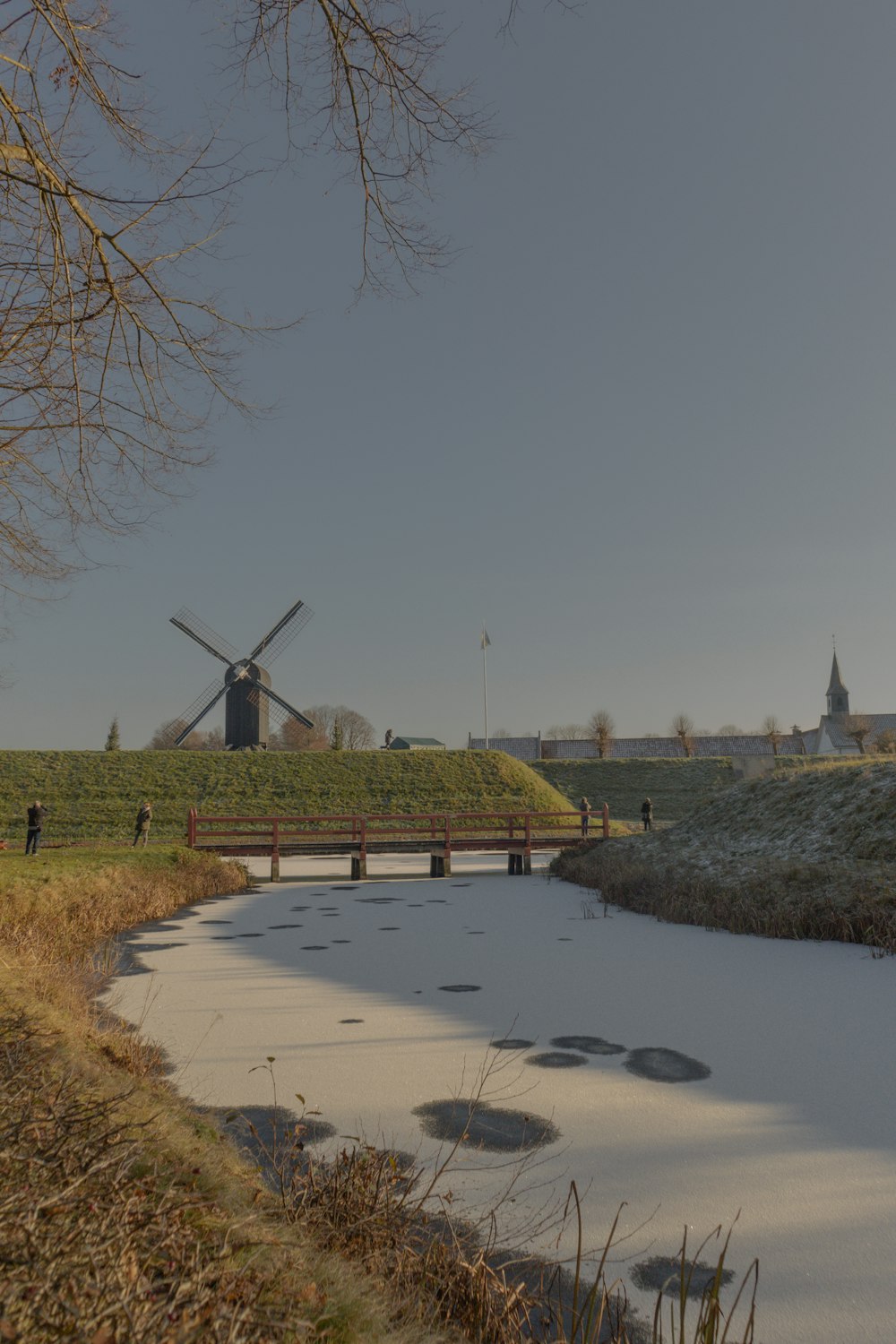 a river running through a field next to a windmill