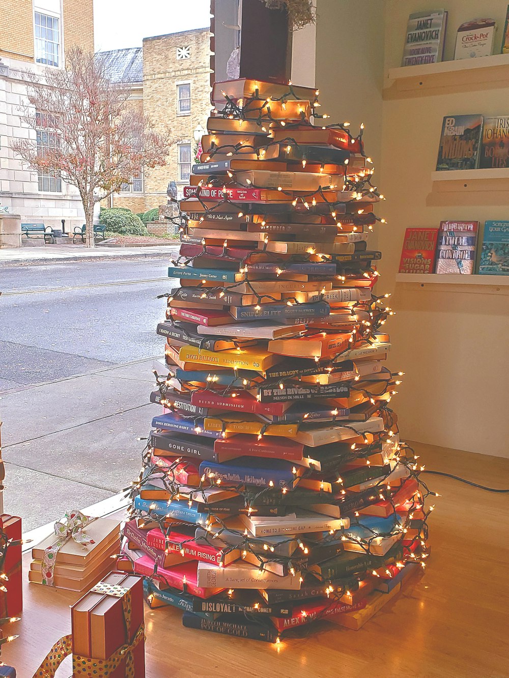 Uma árvore de Natal feita de livros em um chão de madeira