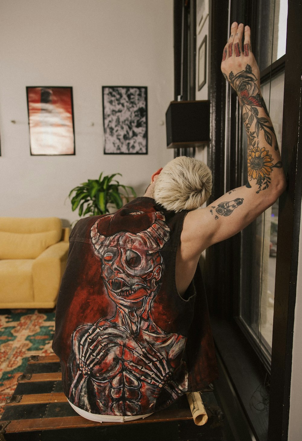 a woman with a tattoo on her arm reaching out of a window