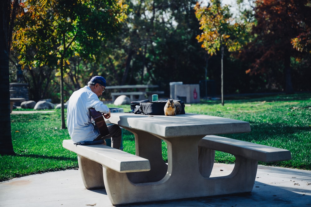 a man sitting at a cement bench in a park