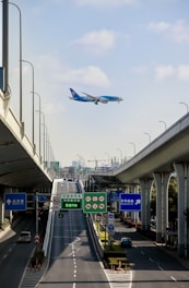A cargo airplane flying above a busy highway with tractor trailers.