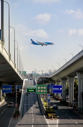 A cargo airplane flying above a busy highway with tractor trailers.