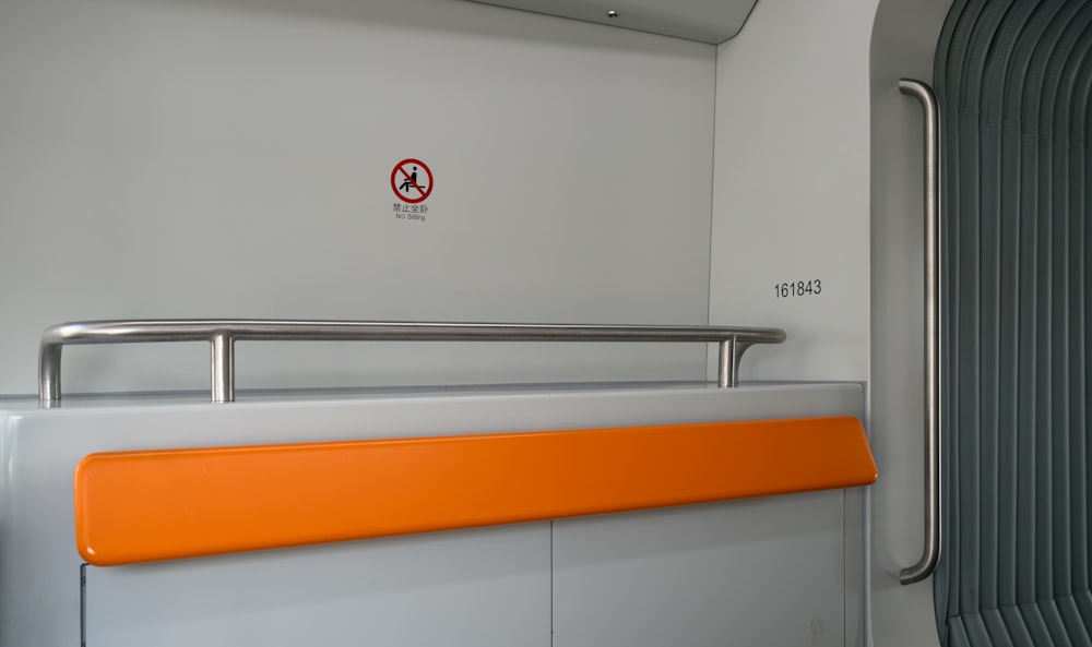 an orange rail on a train next to a door
