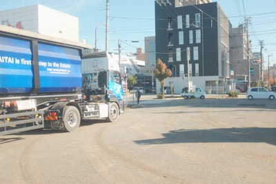 a semi truck driving down a street next to tall buildings
