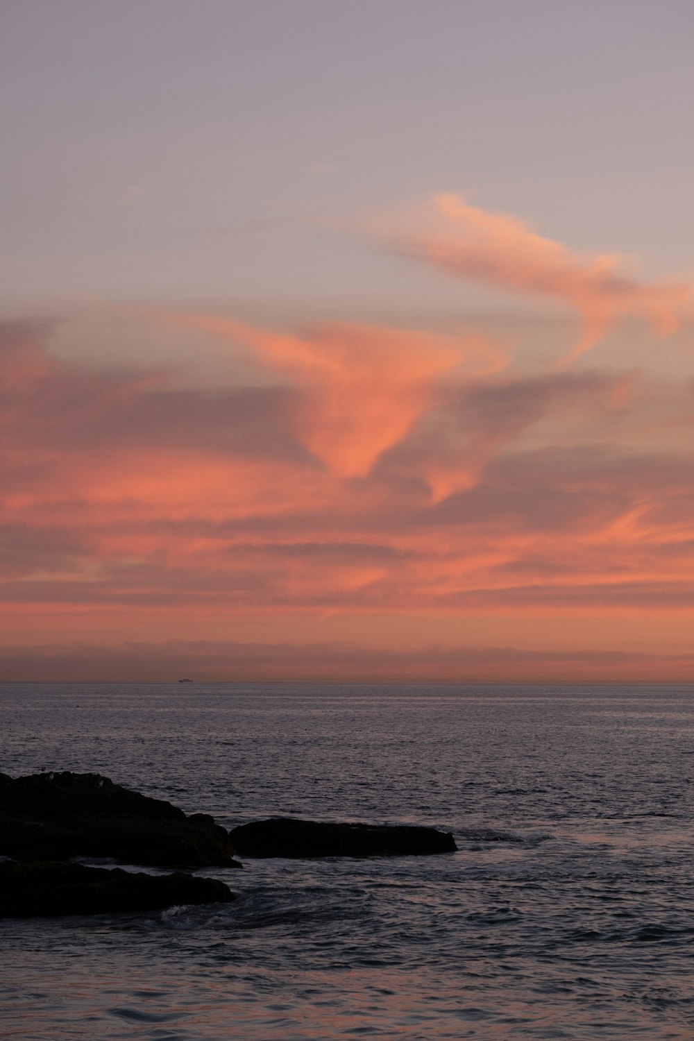 a sunset over the ocean with a boat in the distance