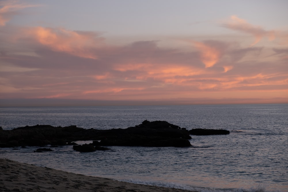 the sun is setting over the water at the beach