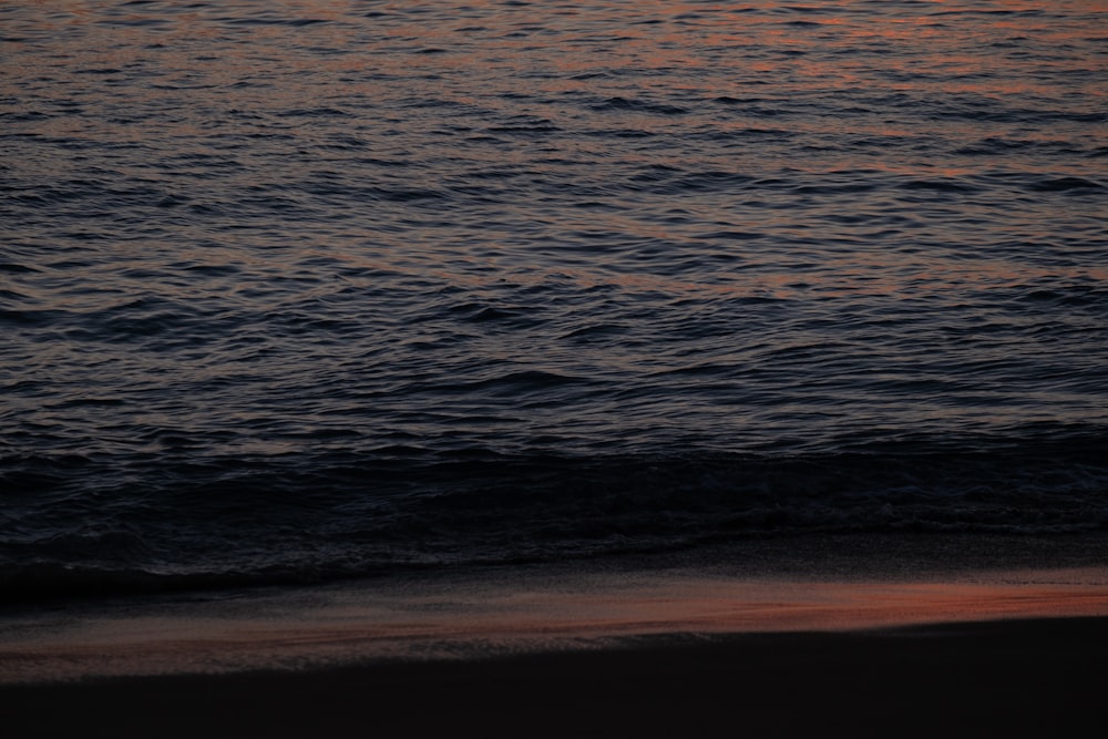 the sun is setting over the water at the beach