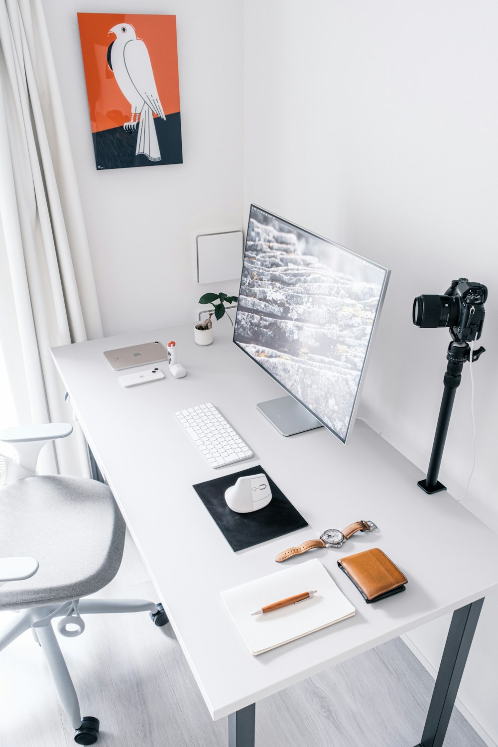 a desk with a monitor, keyboard, mouse and a camera