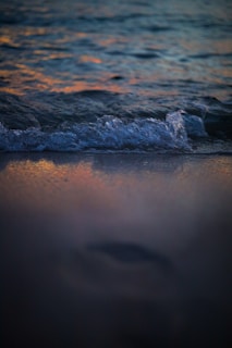 Gentle waves lapping against a sandy shore under a pastel sunset sky.