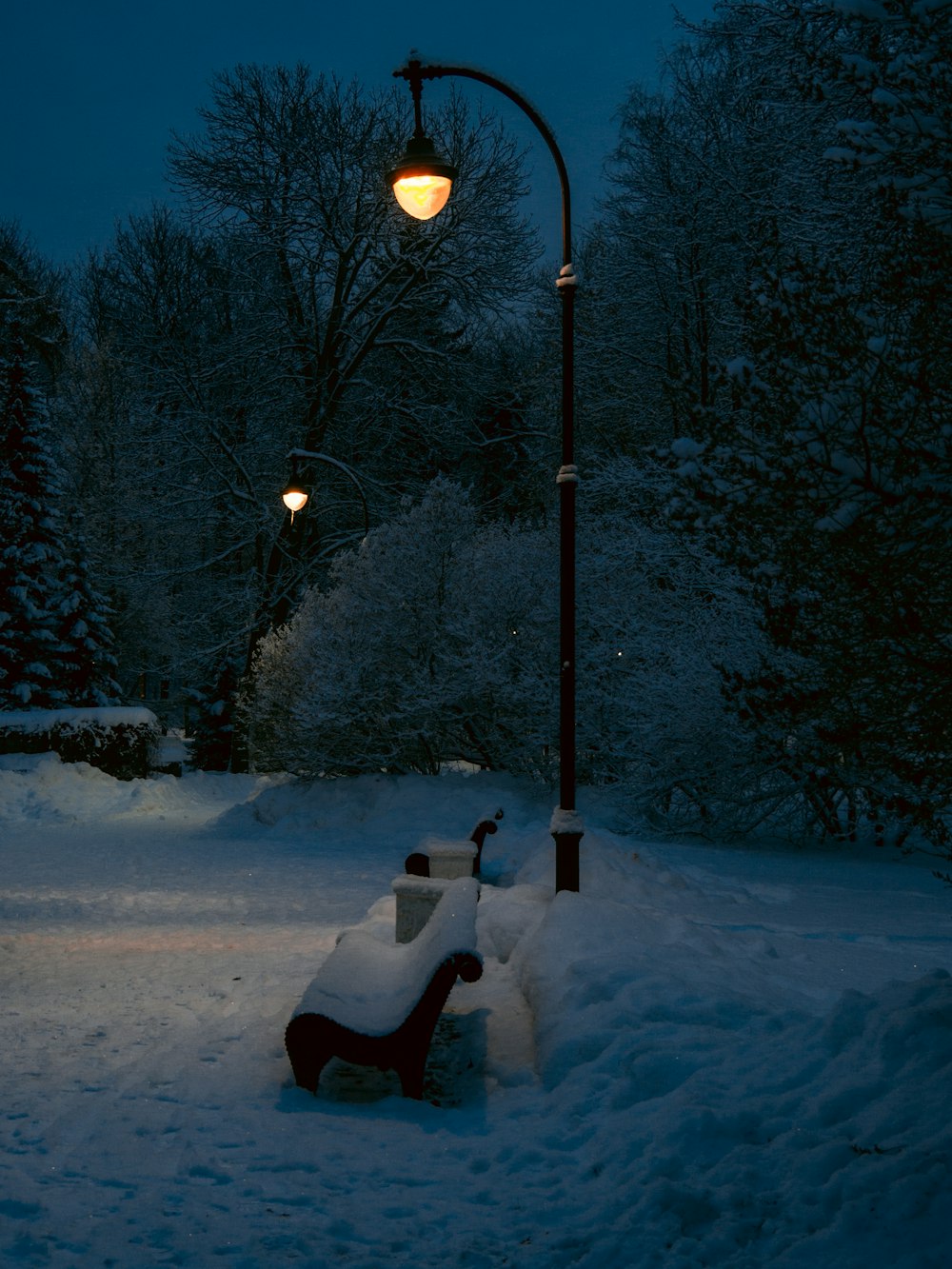 a bench covered in snow under a street light