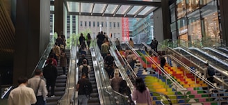 Wide shot of a busy commercial lobby featuring a sleek escalator with people ascending.