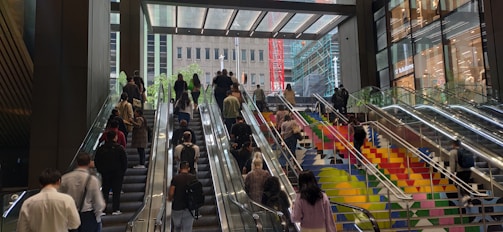 Wide shot of a busy commercial lobby featuring a sleek escalator with people ascending.