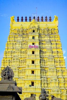 a very tall yellow building with statues on it