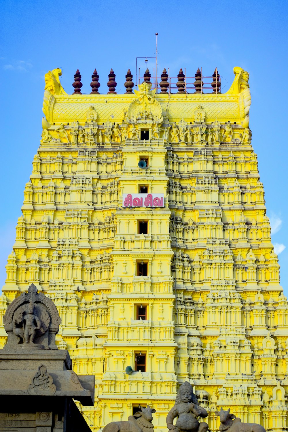 a very tall yellow building with statues on it