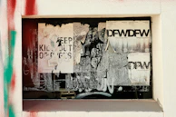 Close-up of a partially peeled propaganda poster revealing a hidden message beneath.