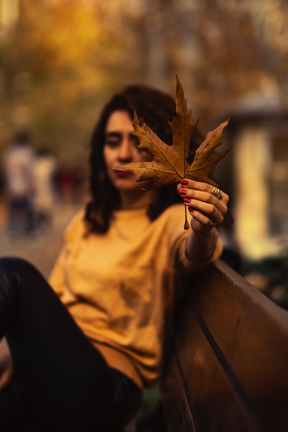 a woman sitting on a bench holding a leaf