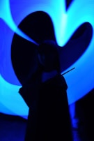 A silhouette of a person holding a wand is depicted against a backdrop of swirling blue neon lights.