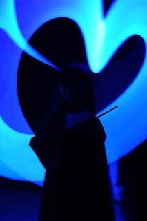 A silhouette of a person holding a wand is depicted against a backdrop of swirling blue neon lights.