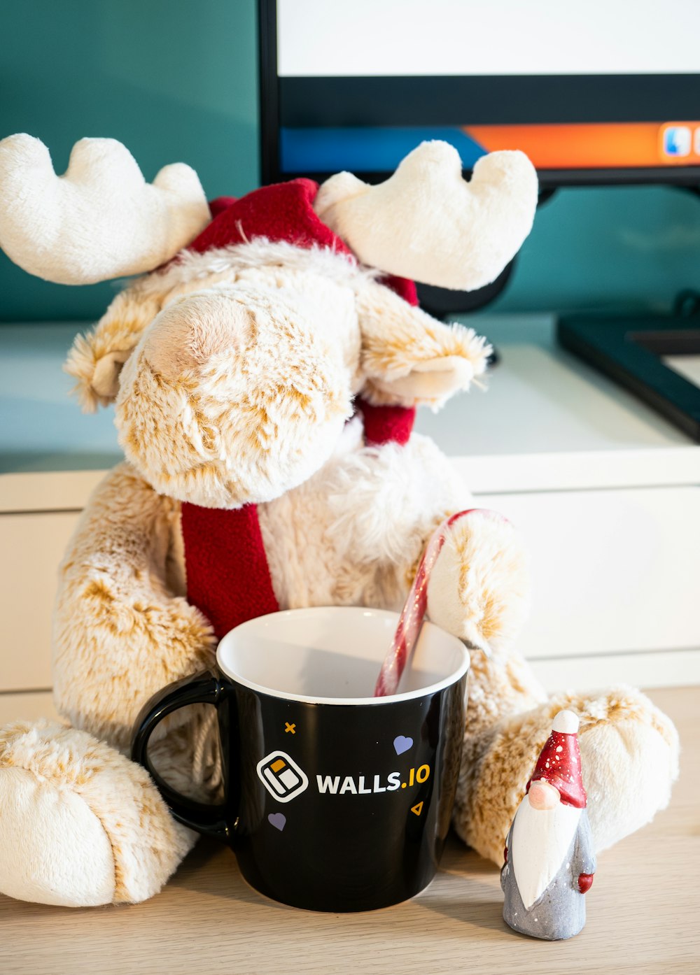 a stuffed moose holding a coffee cup with a candy cane