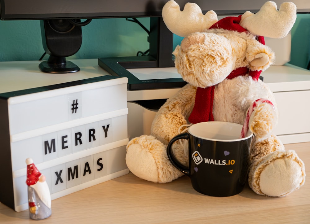 a teddy bear sitting next to a coffee mug