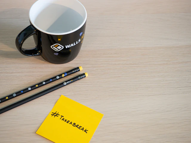 Taza de café junto a material de escritorio y una nota de descanso