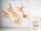 A wire wall grid holds several orange sticky notes attached with decorative wooden clips shaped like holiday figures. Each note has handwritten messages related to marketing campaigns such as 'Christmas Social Media Campaign' and 'New Year's Resolutions Campaign'. To the right of the grid, there is a large ceramic cookie jar labeled 'Mrs. Winterbottom's Delicious Traditions Cookies'. The setting appears clean and organized, suggesting a blend of festive planning and homey warmth.