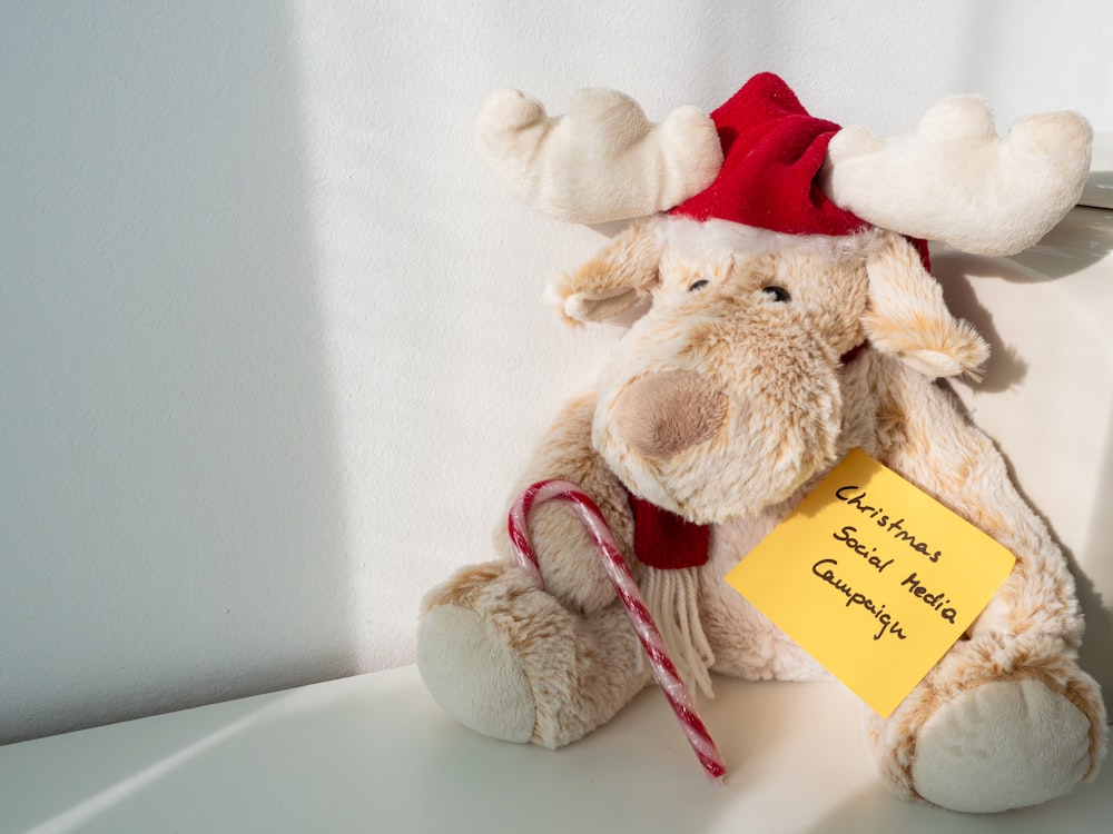a stuffed moose holding a candy cane and a note