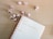A spiral-bound notebook is open on a wooden surface, displaying a page with handwritten text that reads 'Influencer Holiday Takeovers.' Pink ornaments, resembling Christmas baubles, are scattered around the notebook, creating a festive atmosphere.
