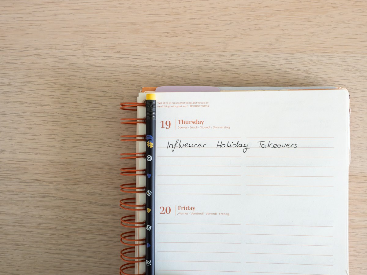A notepad with cookie booth ideas written on it, resting on a wooden table.