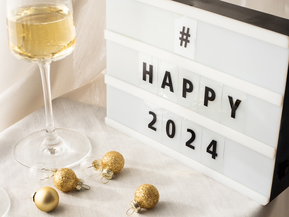a glass of wine and a sign that says happy new year