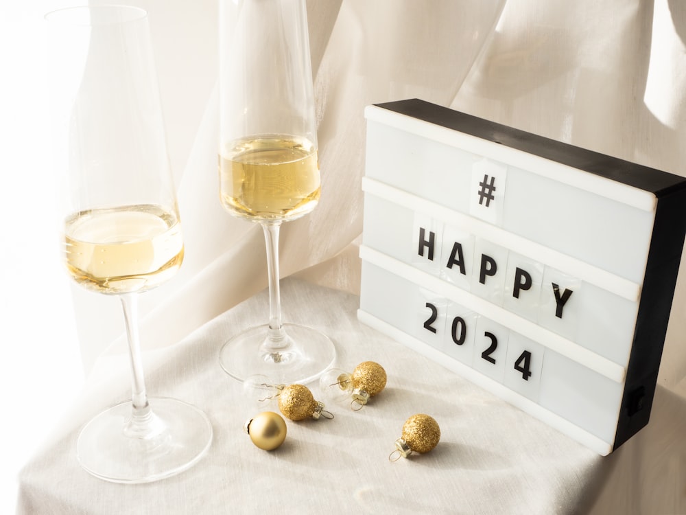 a happy new year sign next to two glasses of wine